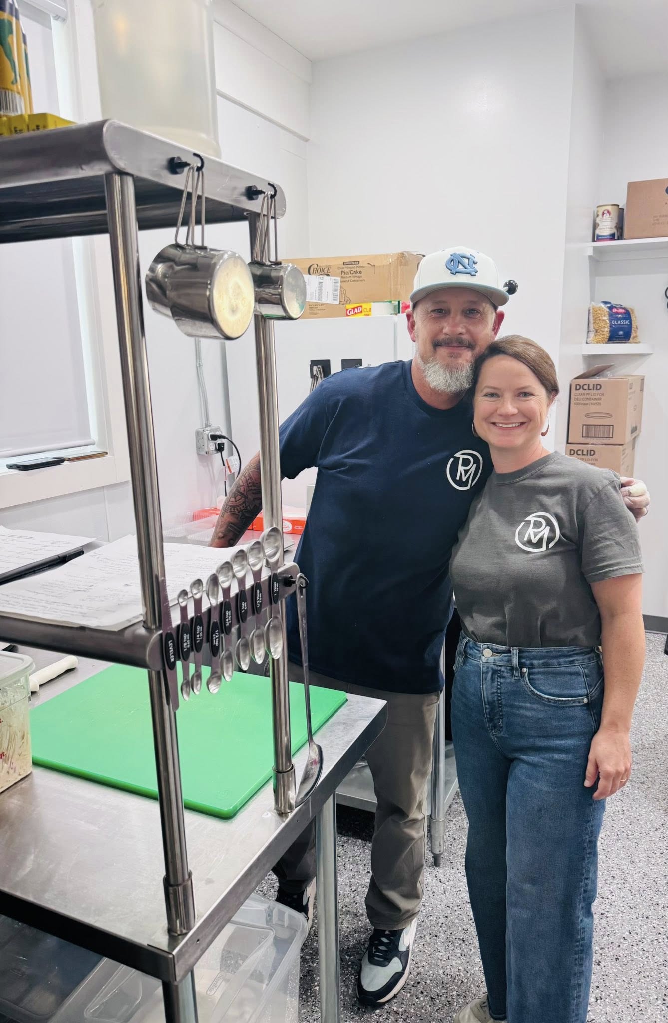 Owners of Roberts Market in matching logo tees inside the shop kitchen